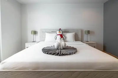 a stuffed penguin is sitting on a bed at ELEGANT Kata sea View Apartmens in Kata Beach