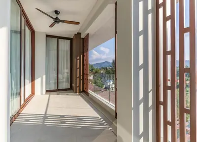 a balcony with glass doors and a ceiling fan at Infinite Ocean Retreats at Angsana Oceanview in Laguna Phuket