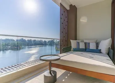a bedroom with a large window with a bed and a table at Infinite Ocean Retreats at Angsana Oceanview in Laguna Phuket