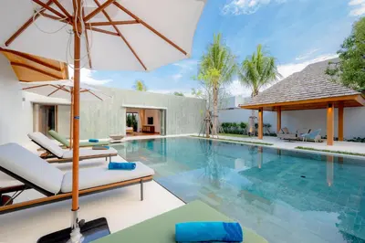 an image of a swimming pool with chairs and an umbrella at Spacious 4BR Private 15m Pool Villa Anchan V10 in Gated Residence in Bang Tao Beach