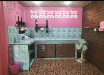 a pink kitchen with a table and a fan at Leamsai House in Ban Laem Sai