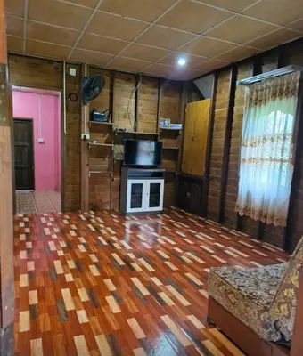 a living room with a wood floor and a stove at Leamsai House in Ban Laem Sai