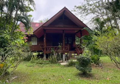 a wooden house with a porch in a garden at Leamsai House in Ban Laem Sai