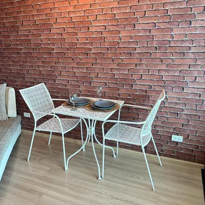 a table and chairs in front of a brick wall at Connext Condominium By January in Ban Tha Khreng