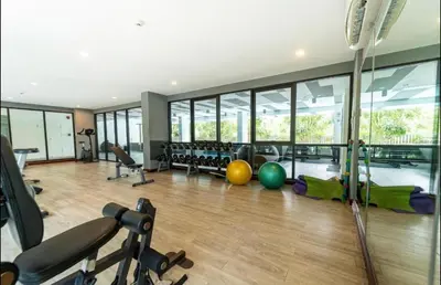 a gym with exercise equipment and a large window at 1 bedroom pool view in Bangtao in Thalang