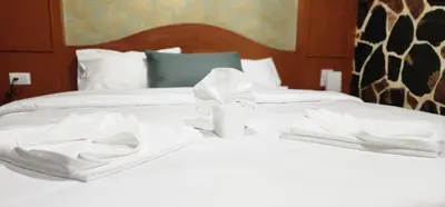 two white beds with white towels on top of them at Arya Suites Patong Beach in Patong Beach