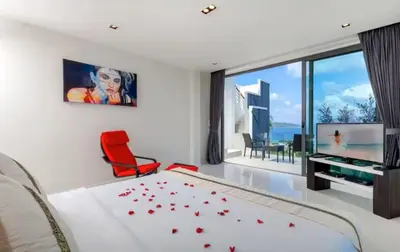 a bedroom with a bed and a red chair at 15 - Ocean View Oasis in Kalim Beach in Patong Beach