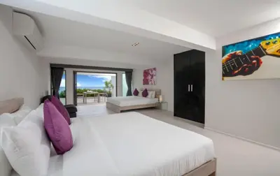 a white bedroom with a large white bed and purple pillows at 15 - Ocean View Oasis in Kalim Beach in Patong Beach