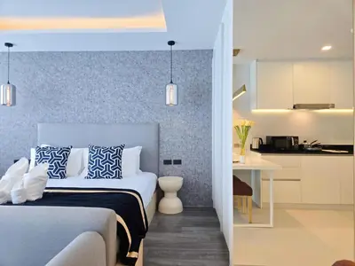 a bedroom with a bed and a kitchen in the background at Karon Utopia in Karon Beach