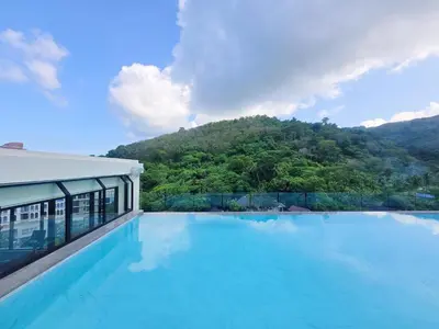 a swimming pool with a mountain in the background at Karon Utopia in Karon Beach