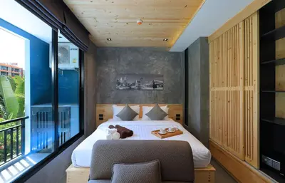 a bedroom with a bed and a chair and a window at ReLife The Windy Naiharn in Rawai Beach