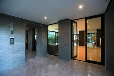 an empty lobby with glass doors and a elevator at ReLife The Windy Naiharn in Rawai Beach
