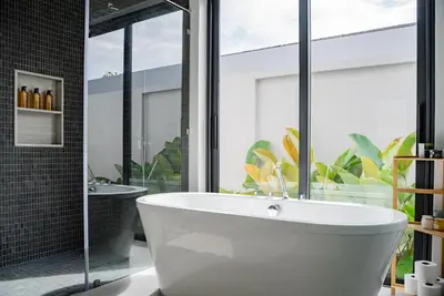 a white bath tub in a bathroom with a window at Botanica Modern Loft by Villacarte in Ban Pak Lak