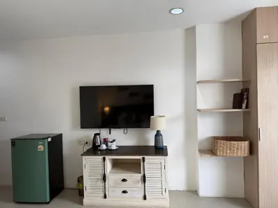 a room with a television and a small table with a refrigerator at Five Loaves Beds Patong in Patong Beach