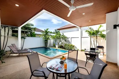 a patio with a table and chairs and a swimming pool at West facing 3br Boutique Pool Villa in Phuket Town