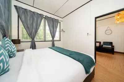 a bedroom with a large white bed and windows at Rawai Cottage House in Rawai Beach