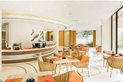 a restaurant with tables and chairs and a counter at Bandara Beach Resort, Phuket in Panwa Beach