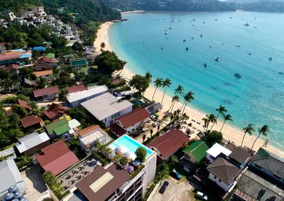 an aerial view of a beach with palm trees and buildings at Bandara Beach Resort, Phuket in Panwa Beach