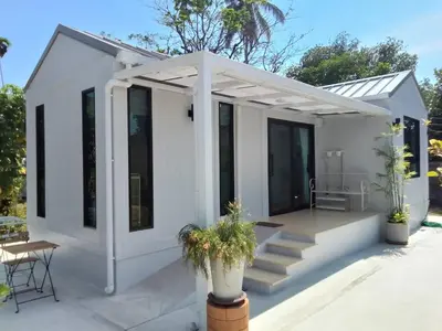 a white tiny house with a porch and stairs at Little Sweet Home in Phuket Town