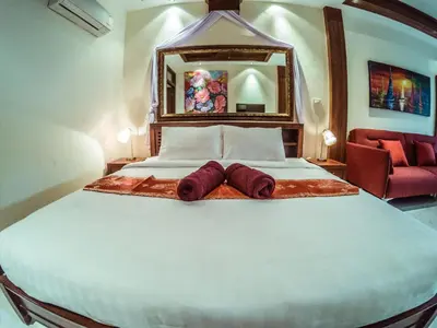a bedroom with a large bed with two robes on it at Baan Sung Apartments in Kamala Beach