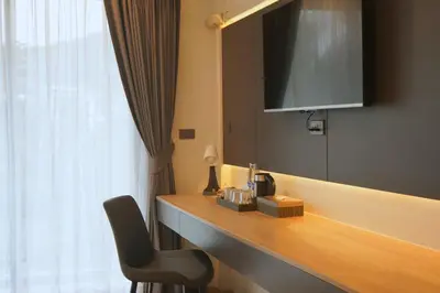 a room with a desk with a television and a chair at Seaside Naithon Phuket - Newly Opened in Nai Thon Beach