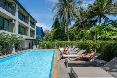 two people sitting on lounge chairs next to a swimming pool at Seaside Naithon Phuket - Newly Opened in Nai Thon Beach