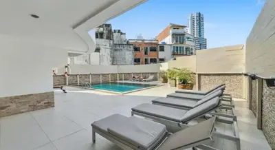 a patio with chairs and a swimming pool on a building at Heritage - Modern Studio shared Pool, City Centre in Patong Beach