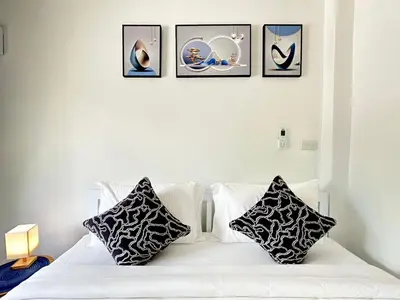 a white bed with four pictures on the wall at Sachi House Stay Near Muay Thai Gym and Beach in Ban Thalat Choeng Thale