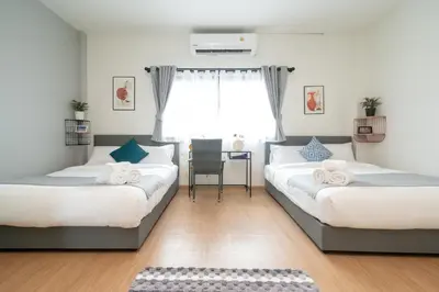 two beds in a room with a table and a window at New Charming Patong Pool villa 5 mins walk Bangla beach in Patong Beach