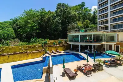 a house with a swimming pool next to a building at Large, Quiet Corner Condo in Patong Beach