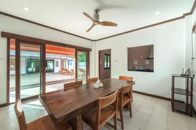 a dining room with a wooden table and a ceiling fan at V155 4BR Large Family Villa Chalong in Chalong