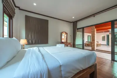 a bedroom with a large white bed and a patio at V155 4BR Large Family Villa Chalong in Chalong
