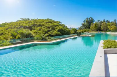 an infinity pool with trees in the background at Laguna Beachside residences apartamens, walking distance to the sea in Bang Tao Beach