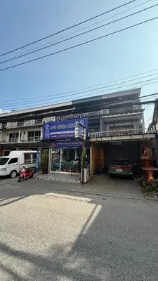 a parking lot with cars parked in front of a building at Chalong Paradise Guesthouse in Ban Bang Chak