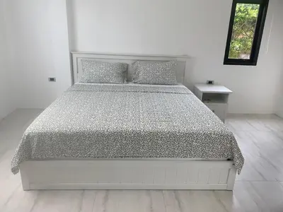a white bed in a white room with a bedspread at Phuket Mali house in Ban Sam Kong