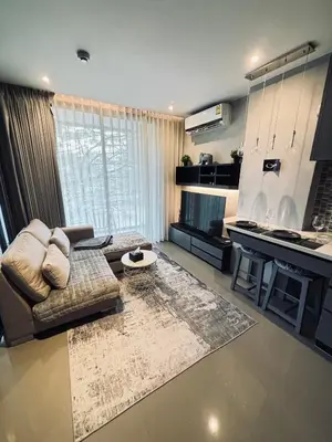 a living room with a couch and a kitchen at Citygate Kamala Condo Paris in Kamala Beach