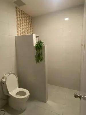 a bathroom with a toilet and a plant on the wall at Mali Villa in Ban Suan