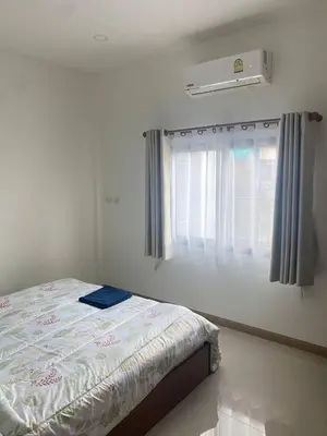 a bedroom with a bed and a window with a air conditioner at Mali Villa in Ban Suan