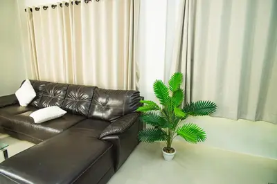a black leather couch in a living room with a palm tree at Songbird Suites - Deluxe 2 Bedroom, 2 Bathroom Apt in Ban Khlong Haeng