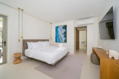 a white bedroom with a bed and a tv at Coco Villas Phuket - Private Pool Villas by Escape Villas in Thalang