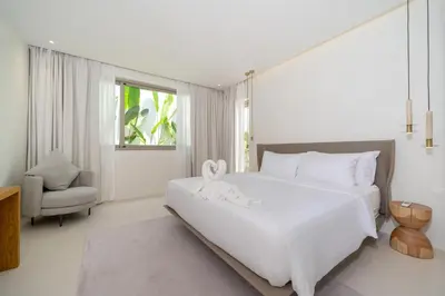 a bedroom with a large white bed and a chair at Coco Villas Phuket - Private Pool Villas by Escape Villas in Thalang