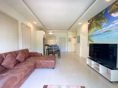a living room with a couch and a large flat screen tv at Oasis 1 Bedroom Apartment In Rawai in Phuket Town