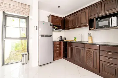 a kitchen with wooden cabinets and a refrigerator at Sunny Stay A8 Charming Residence Close to Nature in Kamala Beach