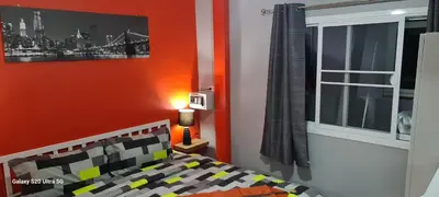 a bedroom with an orange wall with a bed and a window at Karon Homes in Karon Beach