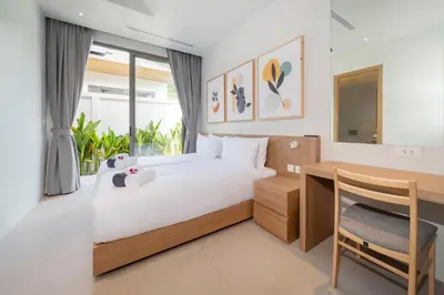 a bedroom with a bed and a desk with a teddy bear at Himmapana Villas - Grand Valley in Kamala Beach