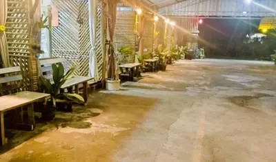 an empty room with benches and tables and plants at Nu Bamboo Backpacker in Phuket