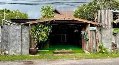 a house with a green yard with a fence at Baibon3 Homestay Thalang Phuket in Ban Na Nai