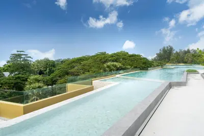 an infinity pool with glass walls and trees at Laguna Beachside Residents in Phuket
