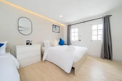 a white bedroom with two beds and a mirror at Winks Beach Patong Phuket in Patong Beach