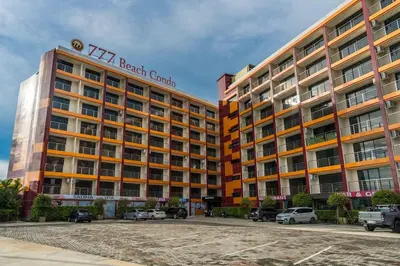 a tall hotel building with cars parked in a parking lot at 1 BR studio 777 Beach Condotel in Mai Khao Beach